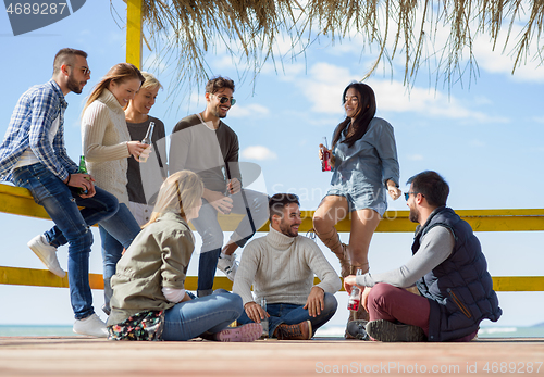 Image of Group of friends having fun on autumn day at beach