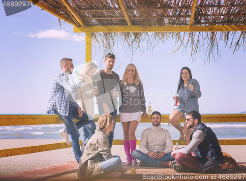 Image of Group of friends having fun on autumn day at beach