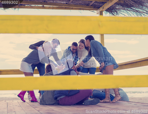 Image of Group of friends having fun on autumn day at beach