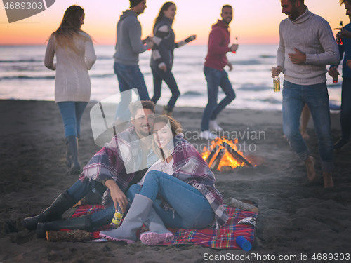 Image of Couple enjoying with friends at sunset on the beach