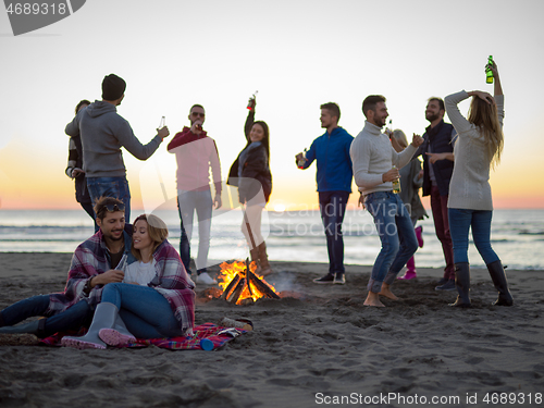 Image of Couple enjoying with friends at sunset on the beach