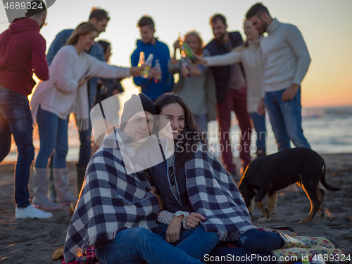 Image of Couple enjoying with friends at sunset on the beach