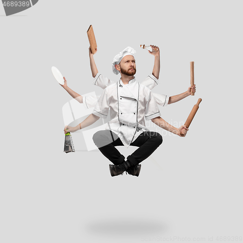 Image of Cooker, chef, baker in uniform multitask like shiva isolated on gray studio background