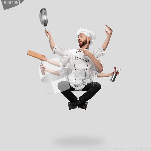 Image of Cooker, chef, baker in uniform multitask like shiva isolated on gray studio background