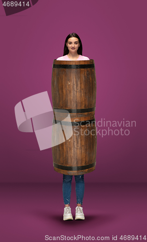 Image of Tall high woman and long barrel isolated on purple studio background. Unusual delighted and long