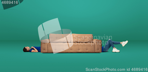 Image of Tall high woman and long sofa isolated on green studio background. Unusual delighted and long