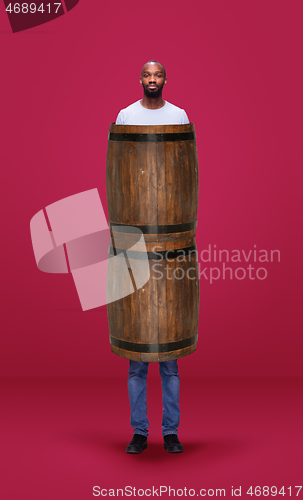 Image of Tall high man and long barrel isolated on pink studio background. Unusual delighted and long