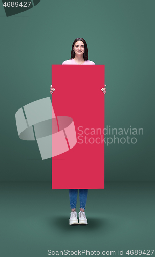 Image of Tall high woman and long pink banner isolated on green studio background. Unusual delighted and long