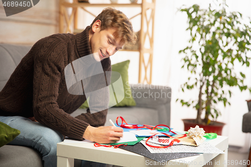 Image of Man making greeting card for New Year and Christmas 2021 for friends or family, scrap booking, DIY