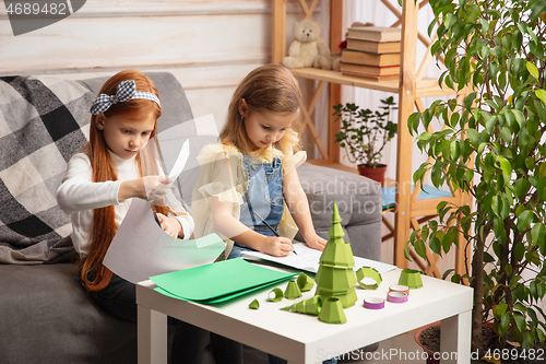 Image of Two little children, girls together in creativity of the house. Happy kids make handmade toys for games or New Year celebration