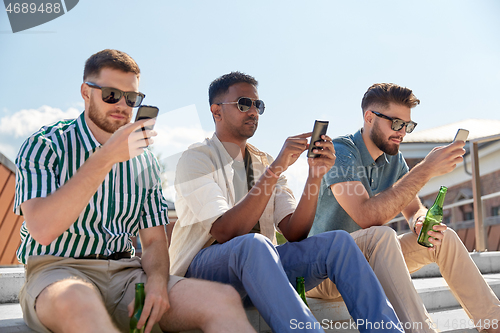 Image of men with smartphones drinking beer on street