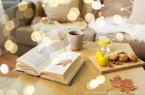 Image of book, lemon, tea and cookies on table at home