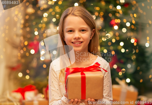 Image of smiling girl with christmas gift at home