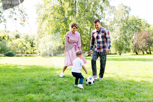 Image of happy family playing soccer at summer park