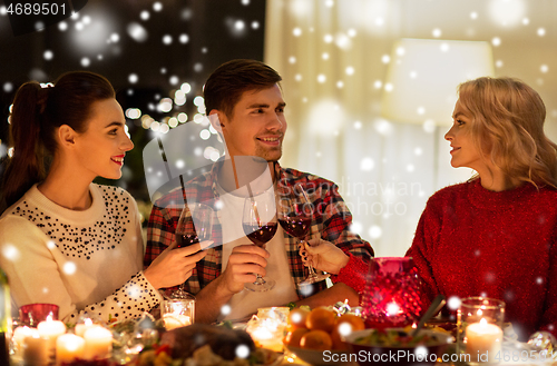 Image of happy friends drinking red wine at christmas party
