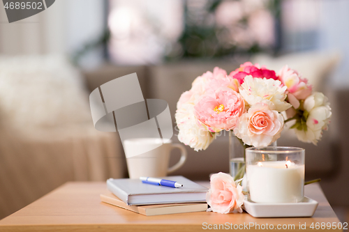 Image of burning candle and flower bunch on wooden table