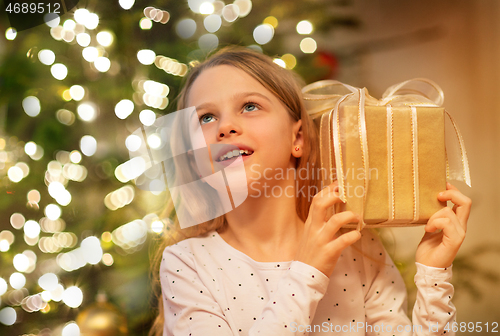 Image of smiling girl with christmas gift at home