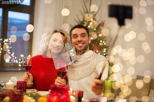 Image of couple taking picture by selfie stick at christmas