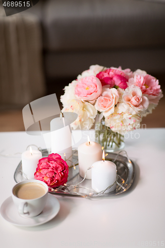 Image of coffee, candles, garland and flowers on table