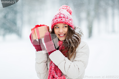 Image of happy young woman with christmas gift in winter