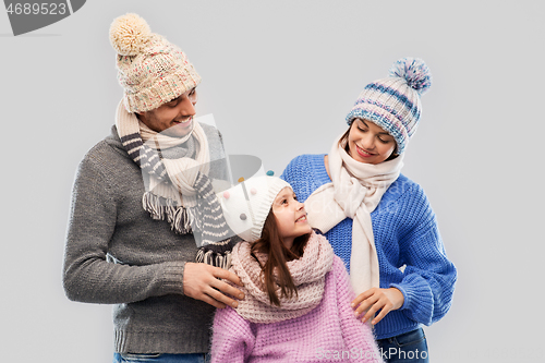 Image of happy family in winter clothes on grey background