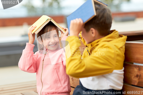 Image of school children with books having fun outdoors