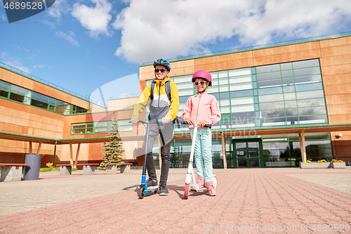 Image of happy school children with backpacks and scooters