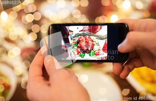 Image of hands photographing food at christmas dinner