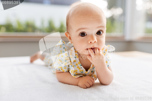 Image of sweet baby girl lying on white blanket