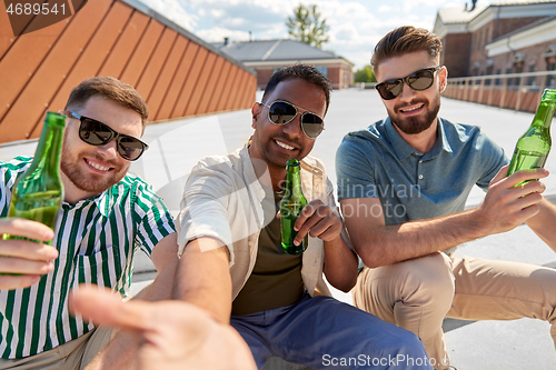 Image of men drinking beer and taking selfie on street