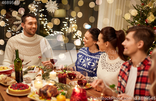 Image of happy friends having christmas dinner at home