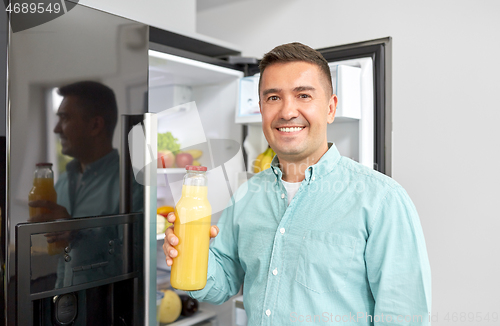 Image of man taking juice from fridge at home kitchen