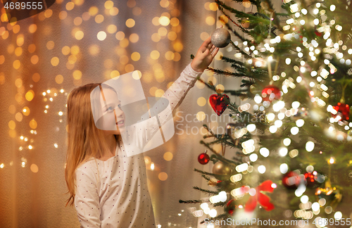 Image of happy girl in red dress decorating christmas tree