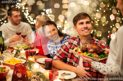 Image of happy friends having christmas dinner at home