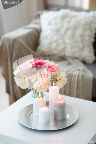 Image of candles burning on table and flowers at cozy home