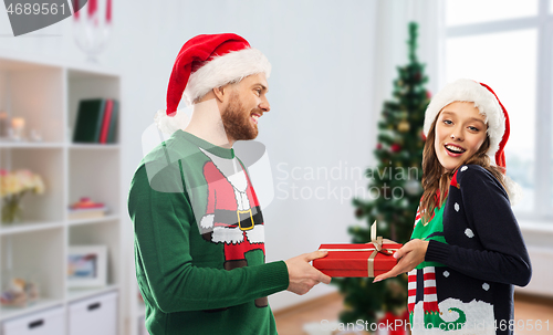 Image of happy couple in ugly sweaters with christmas gift