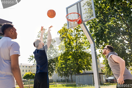 Image of group of male friends playing street basketball