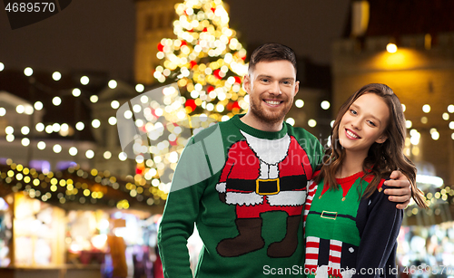 Image of happy couple in ugly sweaters at christmas market