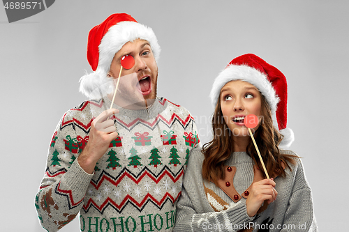 Image of couple with christmas party props in ugly sweaters