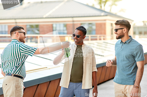 Image of happy male friends drinking beer at rooftop party