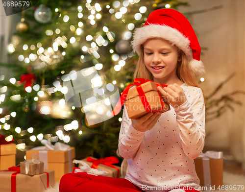 Image of smiling girl in santa hat with christmas gift