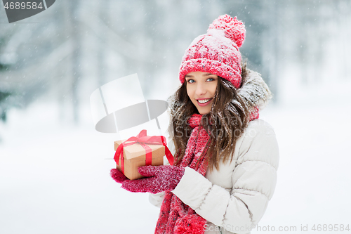 Image of happy young woman with christmas gift in winter