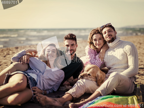 Image of Group of friends having fun on beach during autumn day