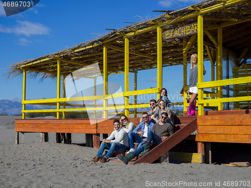 Image of Group of friends having fun on autumn day at beach