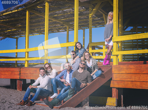 Image of Group of friends having fun on autumn day at beach