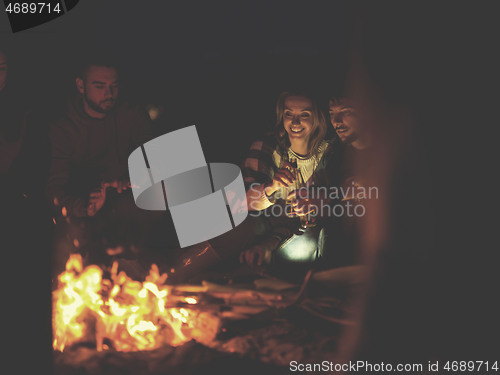Image of Couple enjoying with friends at night on the beach