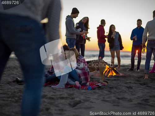 Image of Couple enjoying with friends at sunset on the beach