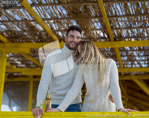 Image of young couple drinking beer together at the beach