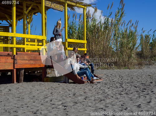 Image of Group of friends having fun on autumn day at beach