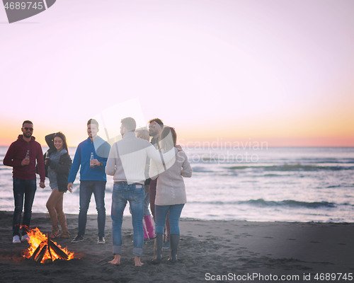 Image of Friends having fun at beach on autumn day